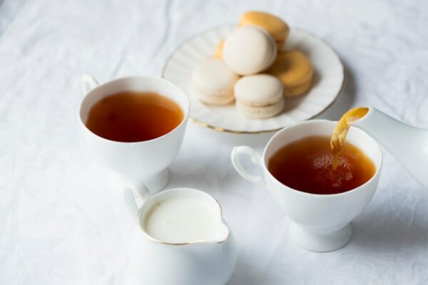 Tea, cookies, and cream are show on a table top.