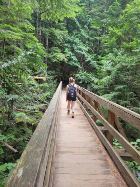 A teen girl crosses a wooden foot bridge along the Lake Serene trail.
