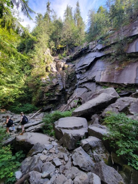 Two teen hikers make their way up large, rocky paths along the trail of Lake Serene.