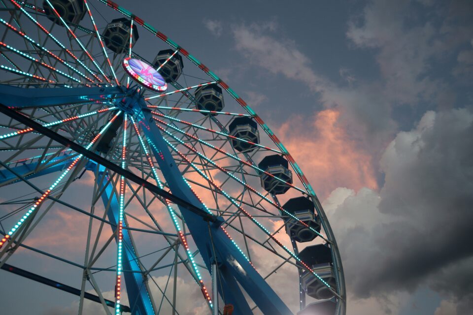 A colorful carnival ride lights up the sky at dusk. 